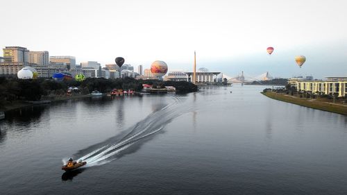 Hot air balloons in city with putrajaya lake against sky