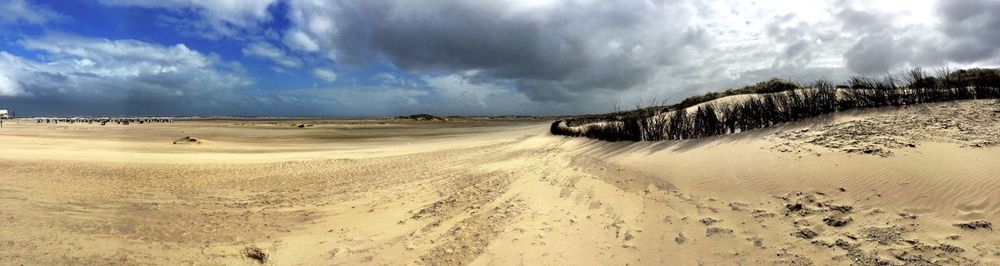 Scenic view of beach against cloudy sky