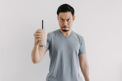 Portrait of young man standing against white background