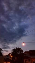 Low angle view of power lines against cloudy sky