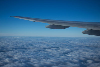 Airplane wing over clouds against blue sky