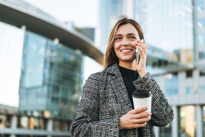 Portrait of young woman standing against buildings