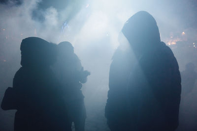 Silhouette people standing against sky at night