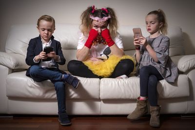 Full length of man using mobile phone while sitting on sofa