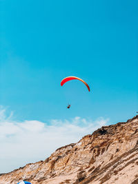 Low angle view of person paragliding against sky