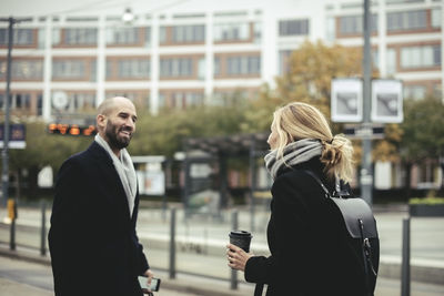 Mid adult businessman talking with businesswoman at tram station