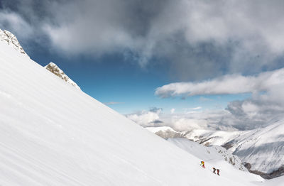 People climbing snowcapped mountains against sky