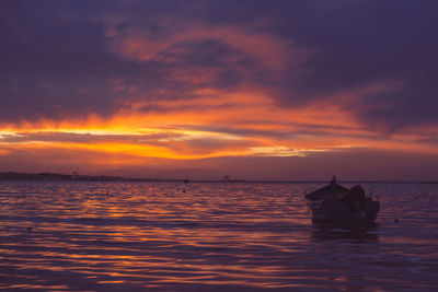 Silhouette boat in sea against sky during sunset