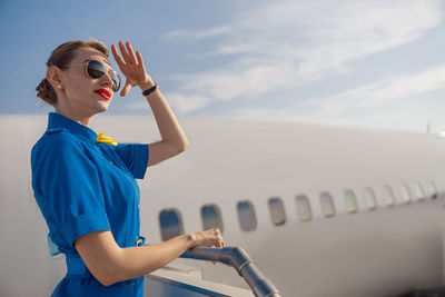 Side view of young woman looking away against sky