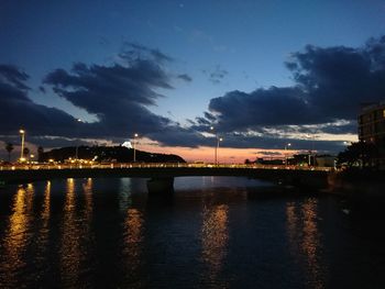 Illuminated bridge over river against sky at night