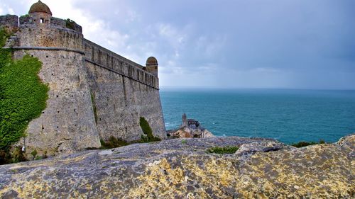 Stone wall by sea against sky