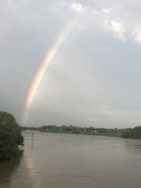 Scenic view of rainbow over lake against sky