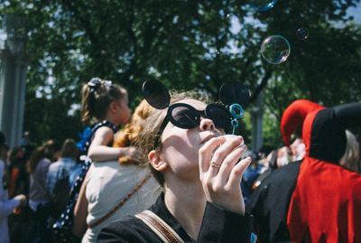 Teenage girl blowing bubbles against crowd