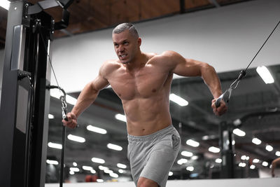 Shirtless man exercising at gym