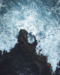 Drone shot of waves splashing on rocks