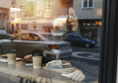 Woman sitting at cafe seen through window