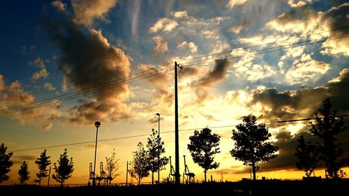 Silhouette trees against scenic sky