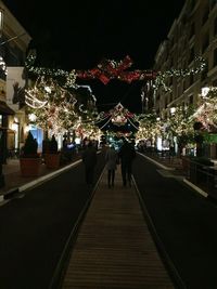 People in illuminated city against sky at night