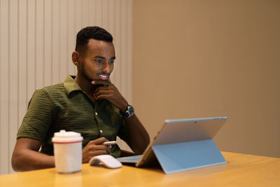 Young man using laptop while sitting on table