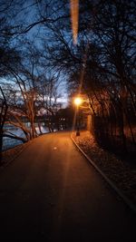 Road amidst trees against sky at night during winter