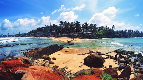 Panoramic view of people on beach against sky