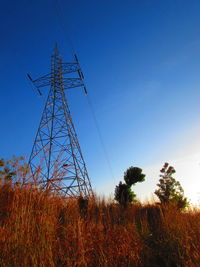 Low angle view of electricity pylon on field