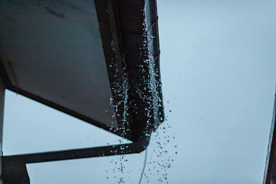 Close-up of icicles against clear sky seen through glass window