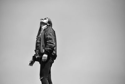 Low angle view of woman standing against clear sky