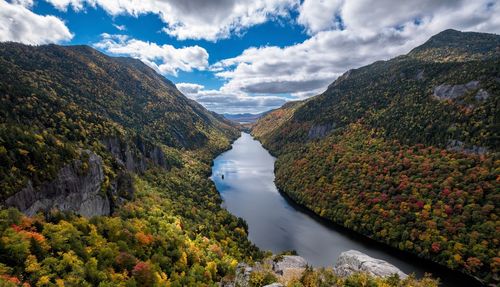 Scenic view of river amidst tree mountains against sky during autumn