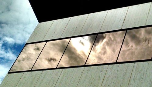 Low angle view of modern building against cloudy sky