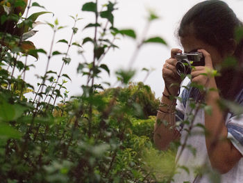 Man photographing plants against sky