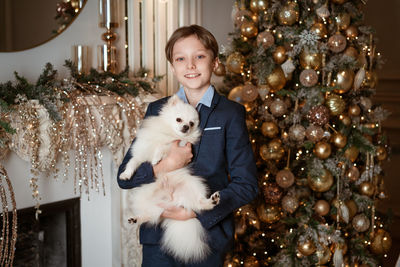 Portrait of a boy and a dog on the background of a christmas tree