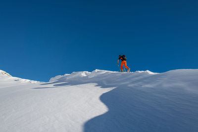 Man skiing on snowcapped mountain against blue sky