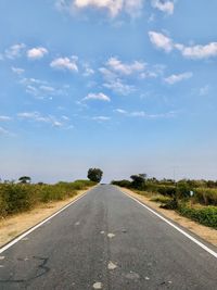 Empty road amidst trees against sky