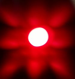Close-up of illuminated red lights against sky at night
