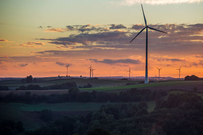 Windmill on field against sky during sunset