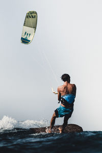 Rear view of shirtless man in sea against clear sky