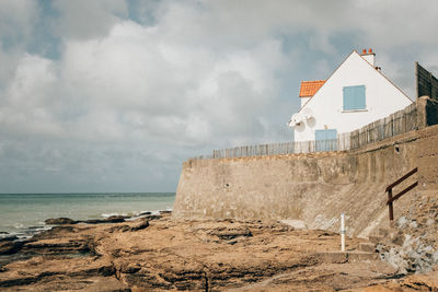 Houses on beach by sea against sky