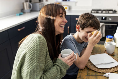 Happy woman enjoying and having breakfast with son at home