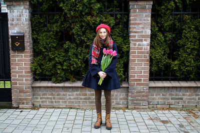 Young french millennial girl in beret and coat with tulips in hands