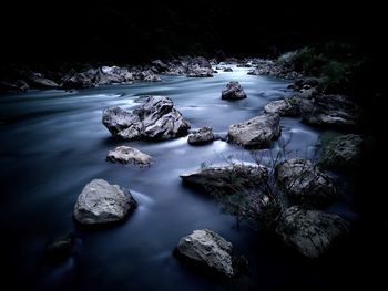 Rocks by river against sky