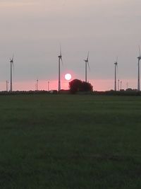 Windmills on field against sky during sunset