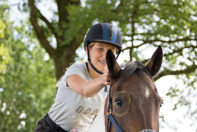 Happy teenager touching ear of horse