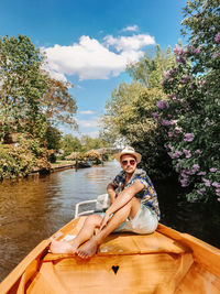 Portrait of man sitting on boat over lake against sky