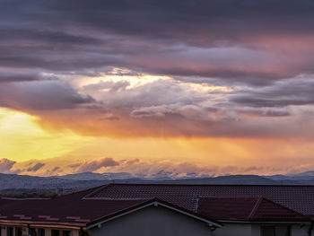 Scenic view of dramatic sky over houses during sunset