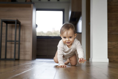 Portrait of cute boy sitting on floor at home