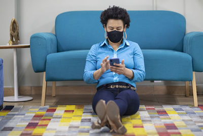 Full length of young man sitting on sofa at home