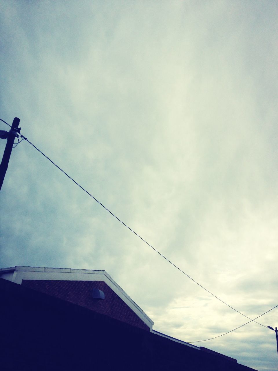 low angle view, sky, architecture, built structure, building exterior, cloud - sky, cloud, bird, cloudy, connection, cable, high section, silhouette, outdoors, day, roof, power line, no people, building, perching