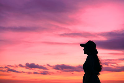 Side view of silhouette woman standing against orange sky