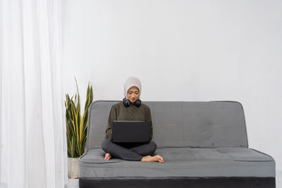 Young man using laptop while sitting on sofa at home